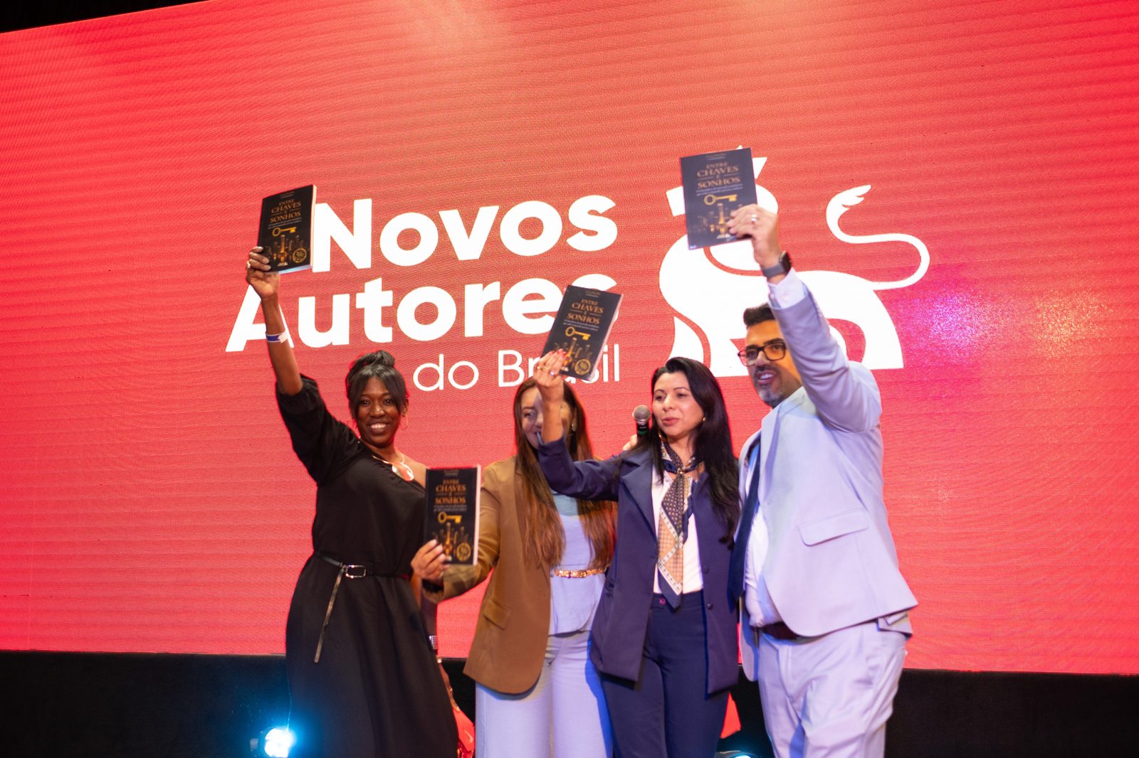 Autores erguendo seu livro no palco da Gala NAB